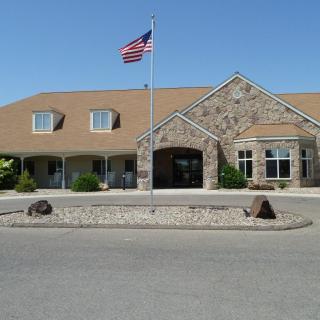 A building with a stone facade and an American flag in front, set against a clear blue sky.