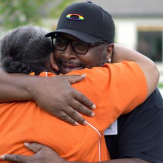 Two people share a warm embrace outdoors, expressing affection and friendship.