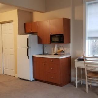 A compact kitchen area in an apartment with a refrigerator, microwave, and cabinets.