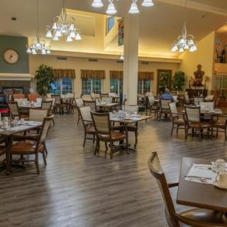 An elegant dining area with neatly arranged tables and chairs, illuminated by chandeliers.