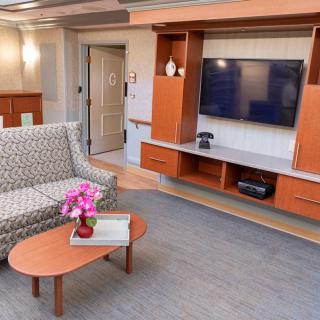 A modern living room featuring a wall-mounted television, a patterned sofa, and a wooden coffee table with decorative items.