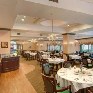 An elegant restaurant dining room with neatly arranged tables and chandeliers.