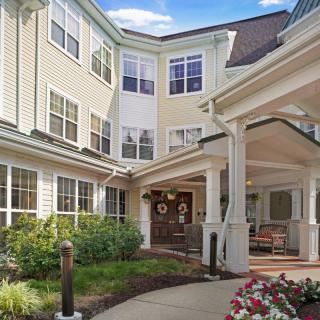 The entrance to a residential building with a covered porch and landscaped surroundings.