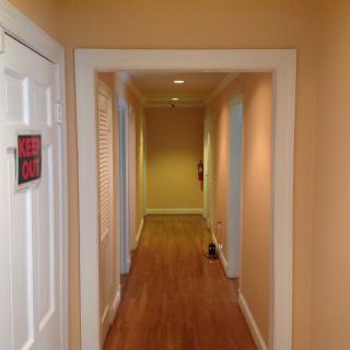 A hallway with wooden flooring and doors on either side.