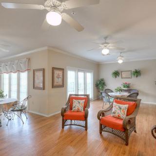 A bright and airy living room with wood flooring, featuring comfortable seating, ceiling fans, and ample natural light.
