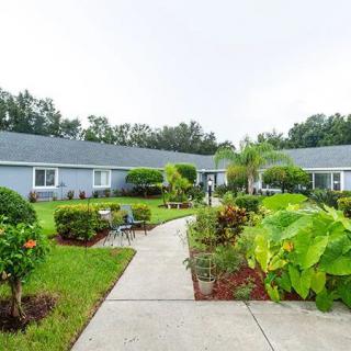 A picturesque garden walkway surrounded by lush greenery and shrubs, leading to a series of connected buildings.