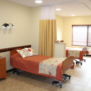 A spacious and well-lit hospital patient room featuring two beds, separated by a curtain for privacy.
