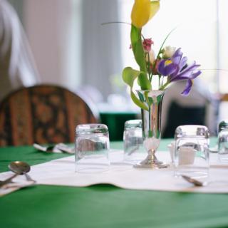An elegantly set dining table with a floral centerpiece and glassware in a restaurant setting.