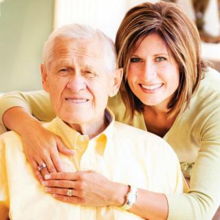 A woman embracing an elderly man, both smiling and showing affection indoors.