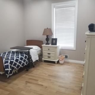 A cozy bedroom with a single bed, nightstand, and dresser.