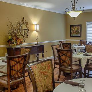 A traditional dining room with elegantly set tables and wooden chairs.