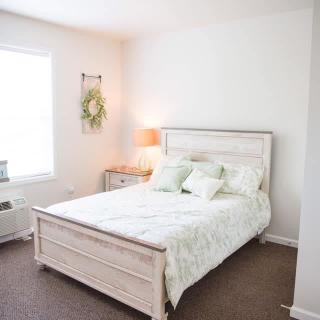 A cozy bedroom with a neatly made bed, soft lighting, and simple decor.