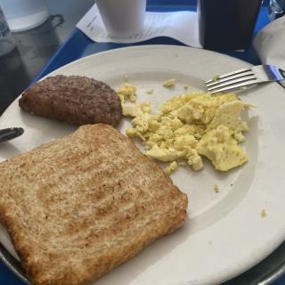A breakfast plate featuring toast, scrambled eggs, and sausage.