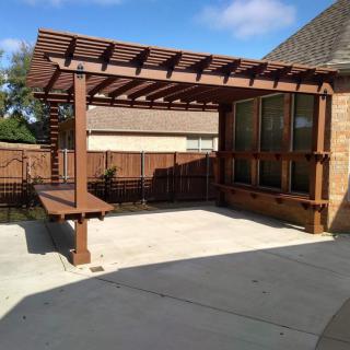 A wooden pergola in a backyard patio setting, providing shade and architectural interest.
