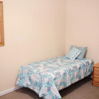 A simple bedroom with a single bed and nightstand.