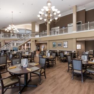 A spacious and elegantly designed dining area with modern furnishings and chandeliers.
