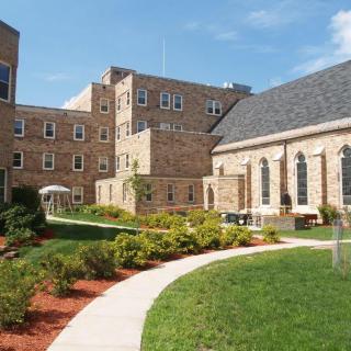 A serene college campus with brick buildings and a landscaped pathway.