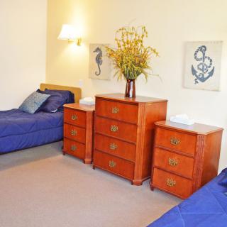 A cozy bedroom with twin beds, featuring a nautical-themed decor and wooden furniture.