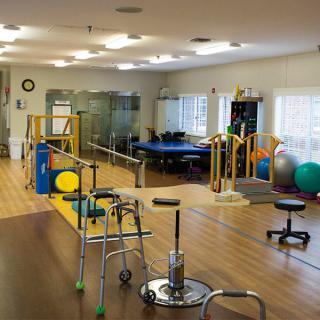A well-equipped physical therapy room with exercise equipment and mobility aids.