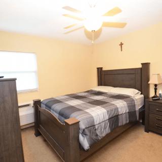 A cozy bedroom with a wooden bed, plaid blanket, and warm lighting.