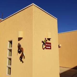 A close-up view of a yellow exterior wall featuring a lizard sculpture and a directional sign.