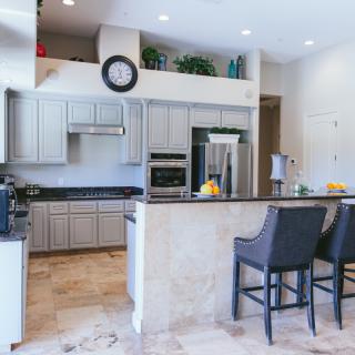 A modern kitchen interior featuring sleek cabinetry, a central island with bar stools, and stainless steel appliances.