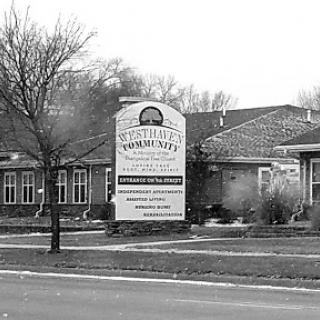 A residential building with a prominent sign in black and white.