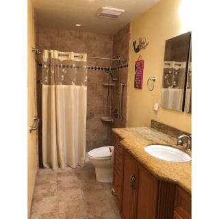 A neatly arranged bathroom with a shower curtain, toilet, and sink on a tiled floor.