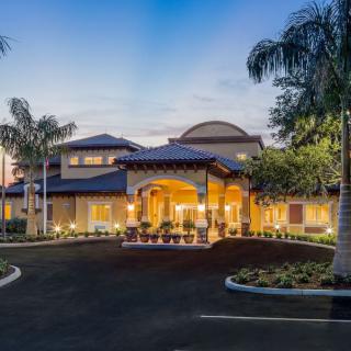Illuminated entrance of a building surrounded by palm trees at night.