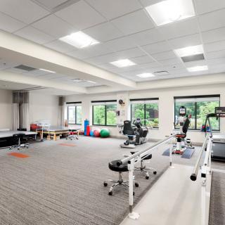 A spacious gym or physical therapy room equipped with exercise equipment and rehabilitation tools.