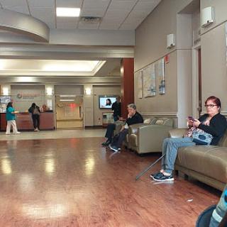 A calm waiting area in a hospital with people seated and others in the background.