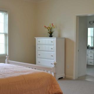 A minimalist bedroom with a bed and white dresser.