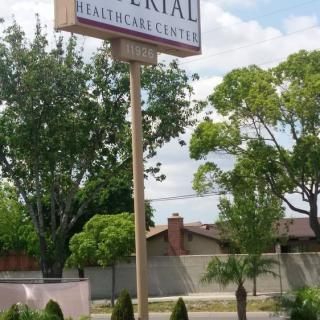 A sign for a healthcare center displayed outdoors with trees and buildings in the background.