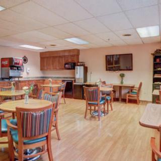 An inviting dining area with several round tables and chairs, adjacent to a kitchenette.