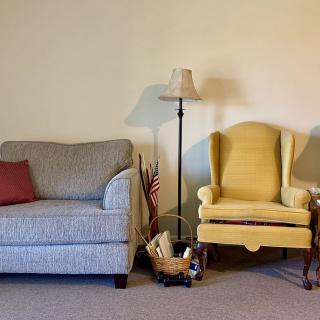 A cozy living room corner with a sofa, armchair, and floor lamp.