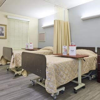 A view of a hospital patient room featuring two beds and privacy curtains.