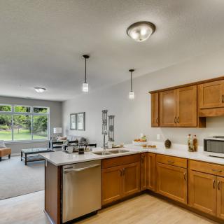 A modern open-concept kitchen with wooden cabinets and stainless steel appliances.