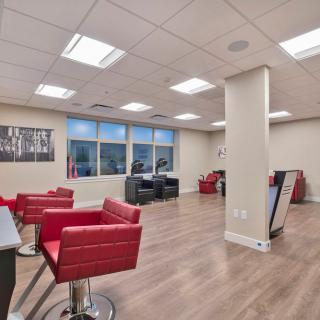 A modern hair salon interior with red chairs and bright lighting.