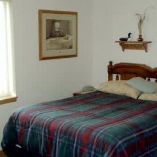 A cozy bedroom with a plaid bedspread and simple decor.