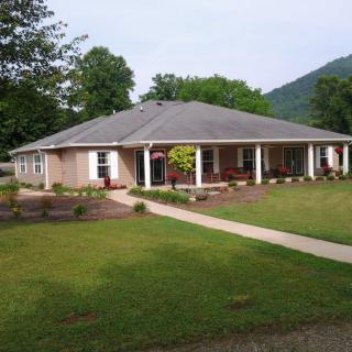 A single-story house with a well-maintained lawn and surrounding trees.