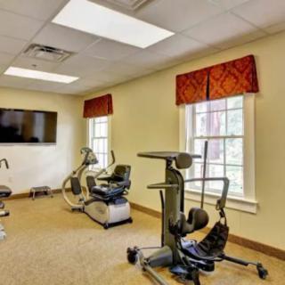 A well-lit exercise room equipped with stationary bikes and a television.