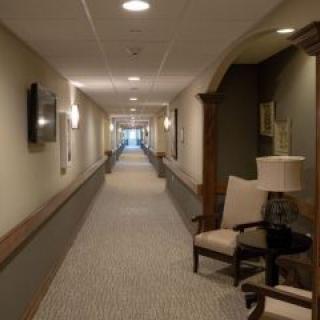 A long, well-lit hallway with chairs and lamps positioned along the sides.