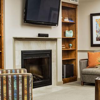 A cozy living room with a fireplace, television, bookshelf, and comfortable seating.