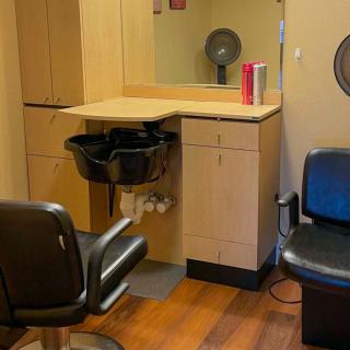 An interior view of a hair salon with styling chairs, a washing sink, and mirrors.