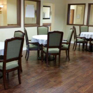 A quiet dining area with tables and chairs set on a wooden floor.