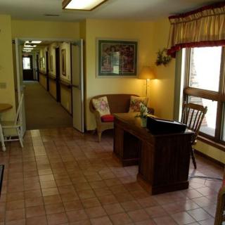 A quiet reception area with a desk and chairs, leading to a long hallway.
