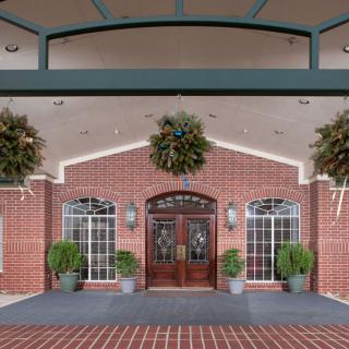 A welcoming building entrance adorned with wreaths and potted plants.