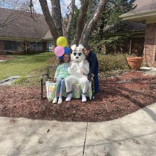 Children enjoying a festive moment with the Easter Bunny, surrounded by colorful balloons in a spring setting.