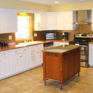 A modern kitchen with white cabinets and a movable island.