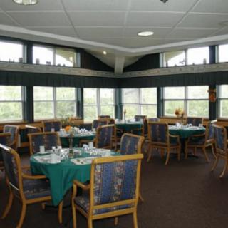 A spacious dining room with multiple tables and chairs set up near large windows.